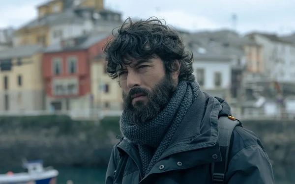 The main character of "La última noche en Tremor" stands outdoors with buildings in the background.