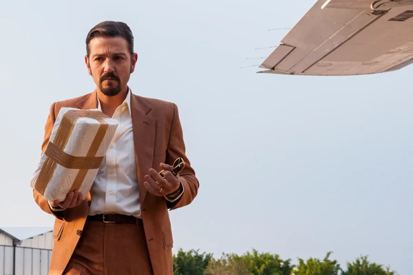 Man carrying a package near an airplane in Narcos: Mexico.