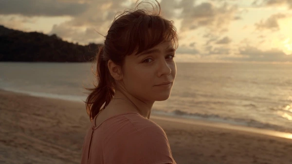 A woman looks back on a beach at sunset in Los Últimos Recuerdos de Abril.